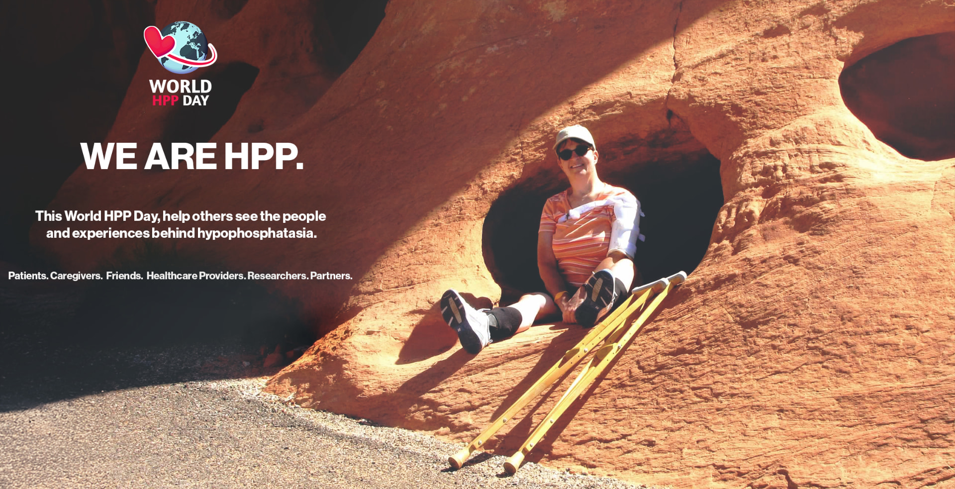 We Are HPP campaign image: a person living with HPP seated with crutches against red desert rock.